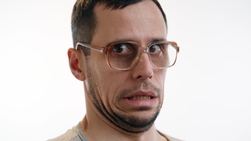 Man in glasses cringes with embarrassment at awkward moment