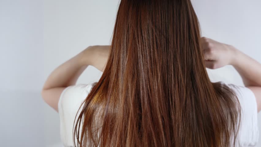 A woman showcases her glossy, flowing hair from behind
