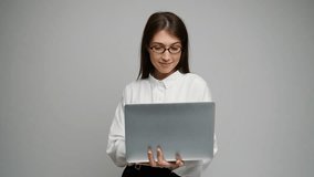 A young woman in glasses stands confidently with a laptop, showcasing her tech-savvy attitude. - Powered by Shutterstock - Get 15% off with code: PIKWIZARD15
