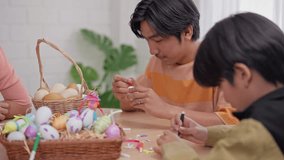 Asian young boy and father coloring Easter eggs on table in house. Happy family, adorable kid with daddy enjoy spend time playing and painting Easter egg on holiday festive in living room at home. - Powered by Shutterstock - Get 15% off with code: PIKWIZARD15