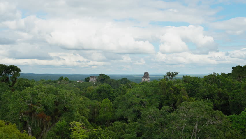 Establishing overview of Temple IV in Tikal National Park, Guatemala, overlooking the jungle canopy under cloudy sky