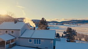 A Snowy Rural Landscape With Houses, Rolling Hills, and Smoke Rising From a Chimney at Sunrise - Aerial Drone Shot - Powered by Shutterstock - Get 15% off with code: PIKWIZARD15