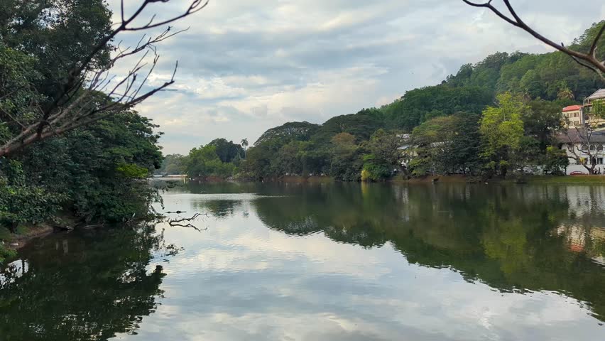 Scenic view overlooking Kandy Lake Kiri Muhuda with forest trees and busy traffic in distance in Kandy, Sri Lanka