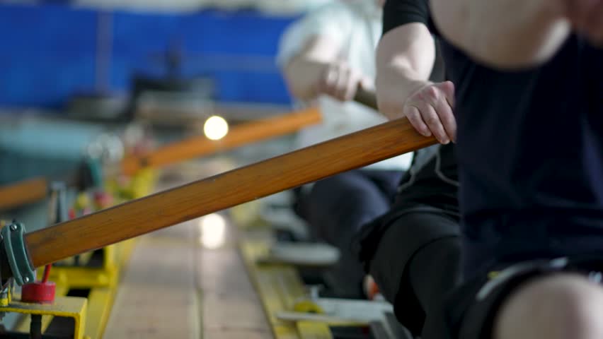 Water sports rowing simulator. Close up rowing team hands work with paddles, preparing for competitions. Arms make circular motions developing flexibility stability, muscle memory and concentration