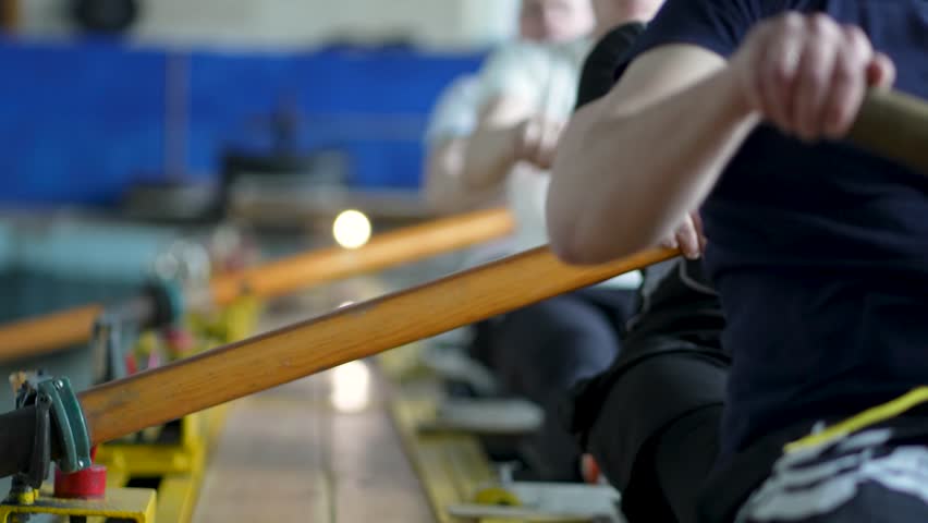 Water sports rowing simulator. Close up rowing team hands work with paddles, preparing for competitions. Arms make circular motions developing flexibility stability, muscle memory and concentration