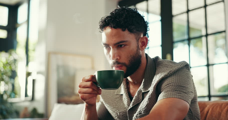 Home, couch and man with coffee for thinking, espresso and comfortable on weekend in living room. House, male person and blow in morning for hot cappuccino, beverage and relax with thoughts on sofa