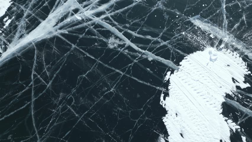 Abstract view of pure dark Baikal ice with cracks. Flying over winter Lake Baikal. top view