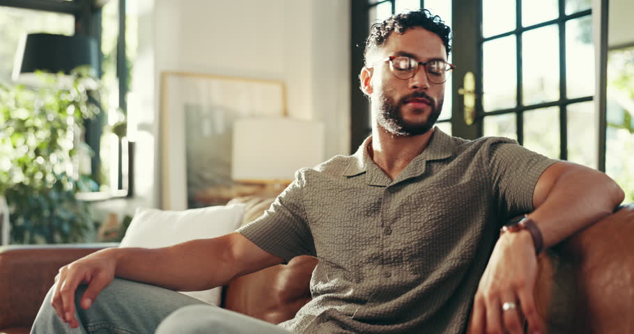 Home, sofa and face of happy man for relax, comfortable and self care for wellness in living room. House, male person and portrait on couch for chilling, resting and smile with peace in lounge