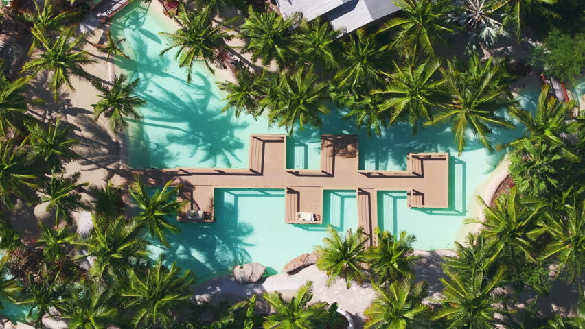 Experience the stunning aerial view of Sunset Key in Key West, Florida, showcasing a lovely pool area with vibrant palm trees and clear water, perfect for relaxation and leisure