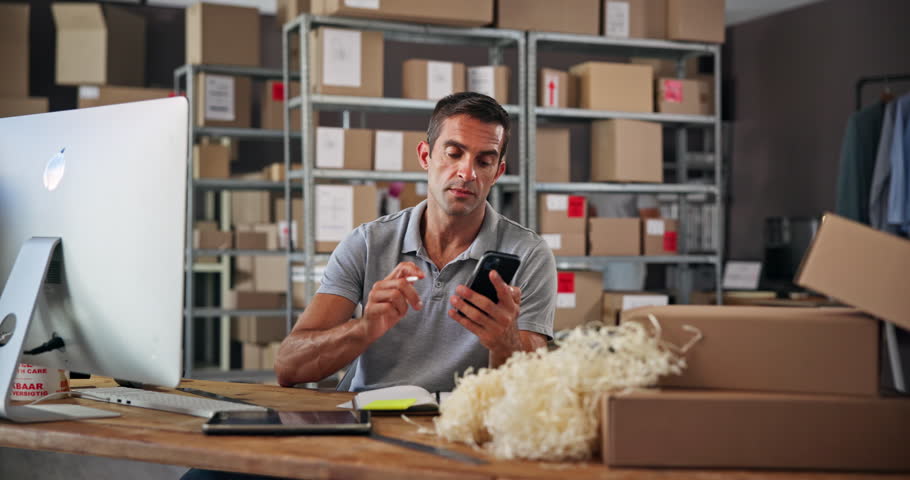 Small business, phone call and man with order, boxes and preparing for delivery with notes and logistics. Warehouse, entrepreneur and person with stock for supply chain, communication and online shop