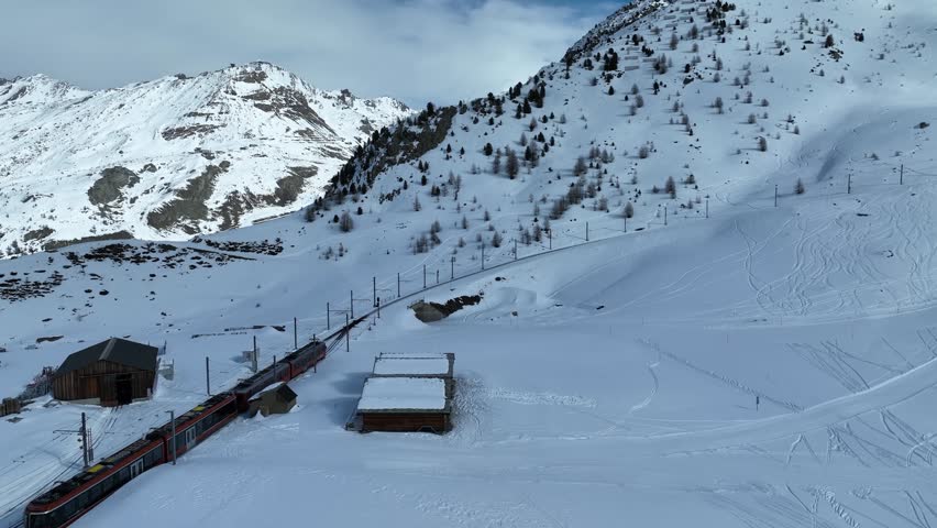 Aerial reveal shot of Gornergrat Bahn train crossing the Riffleboden station toward to Gornergrat summit. Swiss Alps, Switzerland travel journey trip