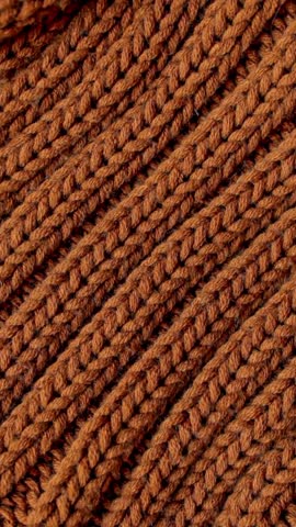 Close-up of brown chunky knit wool fabric. Versatile backdrop for demonstrating cold weather, comfortable clothing, home comfort, designer accessories and eco-friendly design