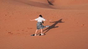 Young woman boarding down desert sand dune in Dubai - Powered by Shutterstock - Get 15% off with code: PIKWIZARD15