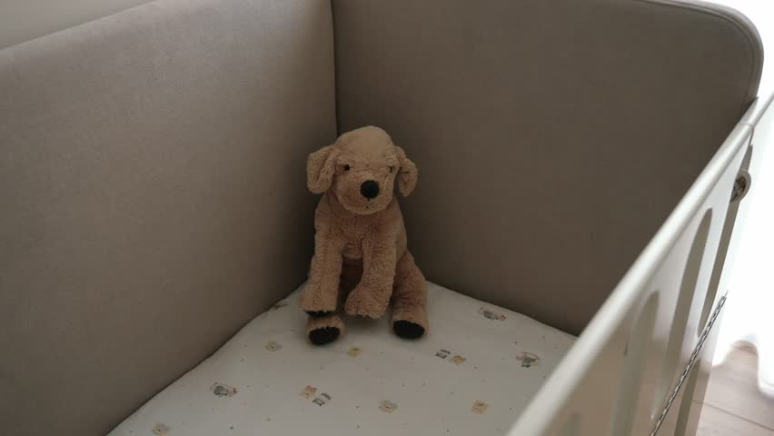 Soft plush dog toy sitting alone in a baby crib, evoking warmth and nostalgia