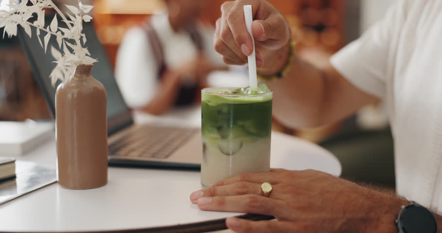 Hands, straw and man in cafe with matcha for morning drink with freelance creative project on laptop. Stir, computer and male journalist with ice green tea latte for energy boost in coffee shop.