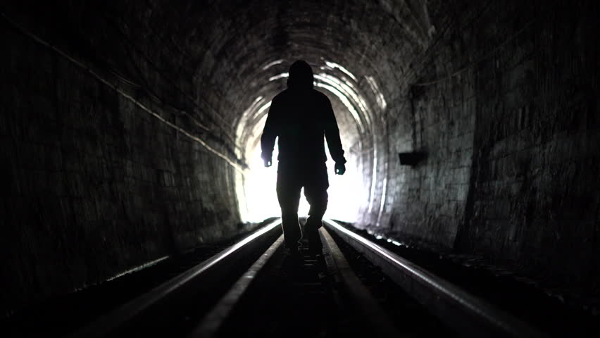 Silhouette of people walking in a railway tunnel