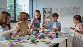 Pupils creating colorful art at collaborative workshop with vibrant materials. Boys girls working on painting projects at lesson classroom. Children concentrating on teamwork enjoying creativity. - Powered by Shutterstock - Get 15% off with code: PIKWIZARD15