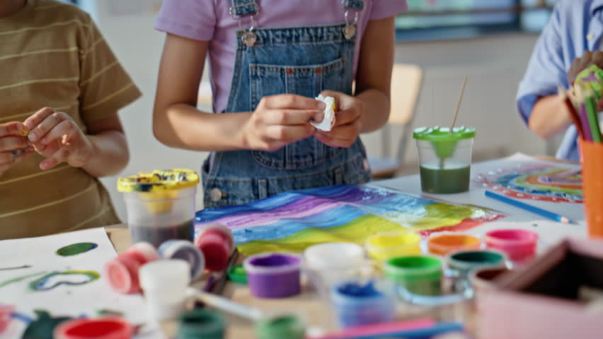 Children creating colorful crafts at art workshop closeup. Little schoolchildren collaborating in vibrant artclass with creative tools. Primary school pupils working together enjoy artistic activity.