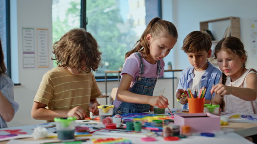 Kids engaged in art activity at elementary school artclass closeup. Group children focused on creativity working with colorful materials in classroom. Creative pupils making handmade crafts together.