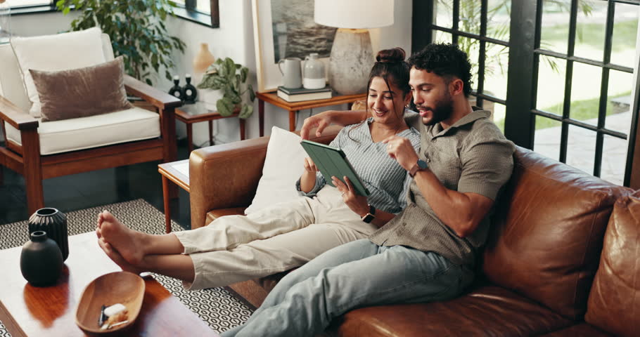 Couple, tablet and talk on sofa in home, relax and embrace with planning vacation in living room. Man, woman and digital touchscreen with app, happy and search for holiday location at apartment