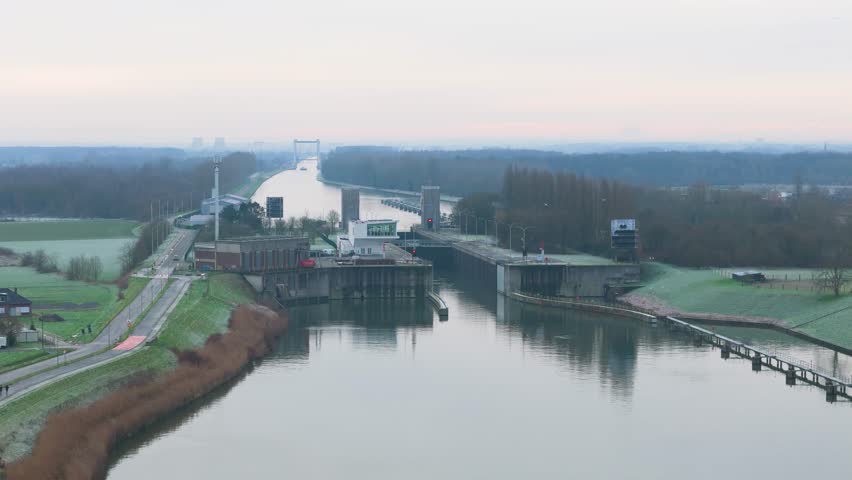river canal ship lock countryside rural belgium cloudy morning winter logistics shipping region circling aerial drone shot operations