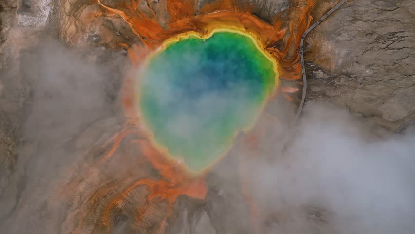 Aerial view of the vibrant grand prismatic spring surrounded by mist and a boardwalk with people, Yellowstone National, Wyoming, United States.