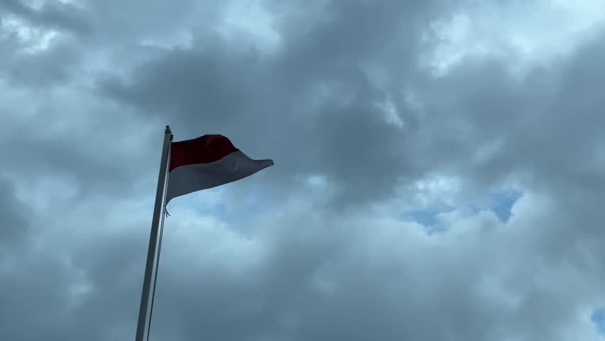 The national flag of Indonesia waving under the cloudy sky