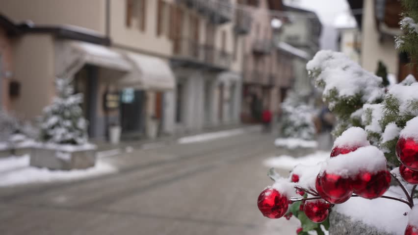 View of snow covered street, shops and shoppers on Via Roma in winter in Courmayeur, Aosta Valley, Italian Alps, Italy
