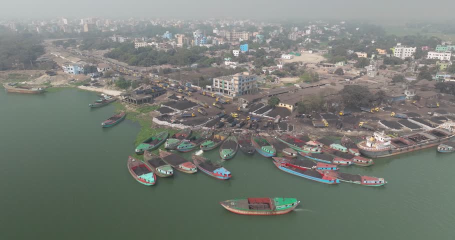 Aerial view of bustling coal factory and busy boats on Meghna River, Bhairab, Dhaka, Bangladesh.