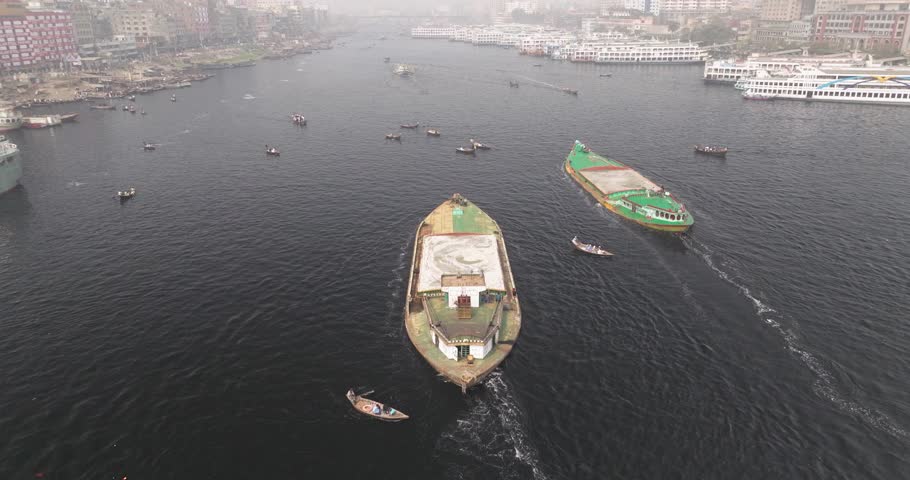 Aerial view of bustling boats on the Buriganga River with a vibrant cityscape at sunset, Sadar Ghat, Dhaka Province, Bangladesh.