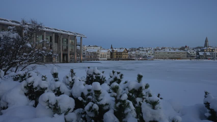 View of frozen Tjornin lake, Lutheran Free Church and Hallgrimskirkja in winter, Reykjavik, Iceland