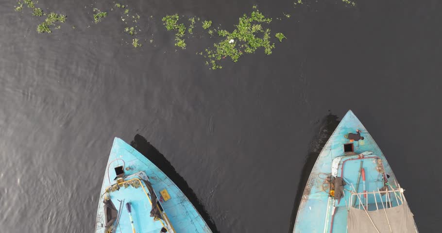 Aerial view of traditional wooden boats on the serene Buriganga River surrounded by greenery, Dhaka, Dhaka Province, Bangladesh.