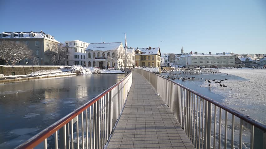 View of snow covered Tjornin Utsynisstaour park and city in background in winter, Reykjavik, Iceland