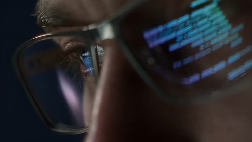 Extreme close-up of a programmers eye with computer code reflecting on glasses, symbolizing cybersecurity, coding, and software development. 