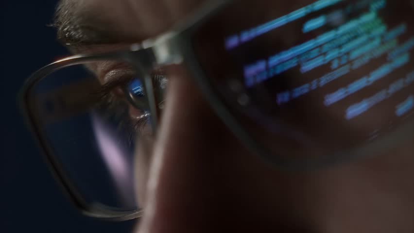 Extreme close-up of a programmers eye with computer code reflecting on glasses, symbolizing cybersecurity, coding, and software development. 
