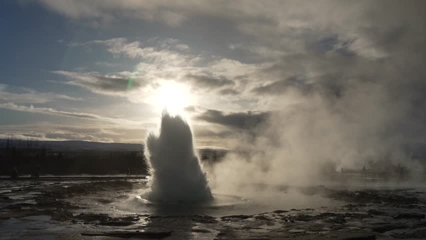 View of the erupting Strokkur geyser at Geysir Hot Springs with sun in background in winter, Golden Circle, Western Region, Iceland