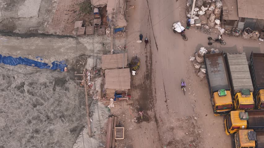 Aerial view of busy traffic with rickshaws, pickups, and trucks amidst dust and smog, Dhaka, Dhaka, Bangladesh.