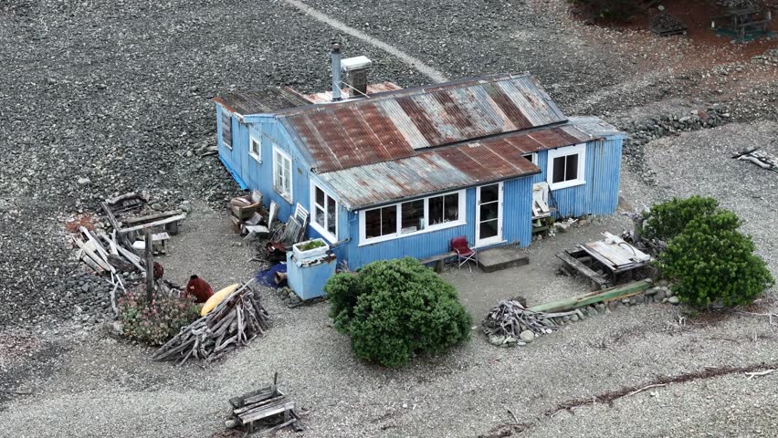 Aerial view of a rustic chalet holiday home with a blue house and rustic roof surrounded by serene nature and bushes, Nelson, Nelson, New Zealand.