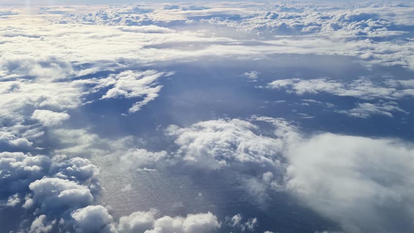 Airplane flying above beautiful clouds over blue ocean
