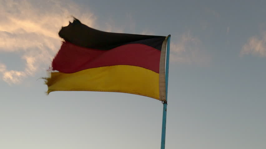 Germany flag on flagpole flutters in the wind, slow motion, A dirty and tattered flag of the Federal Republic of Germany on blue sky with clouds background in the evening