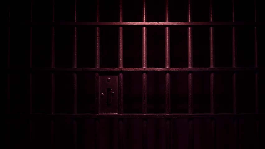 Prison Cell Bars Casting Shadows: Symbolizing Confinement and Loss of Freedom. metal prison cell bars casting shadows on the floor, representing themes of incarceration, confinement