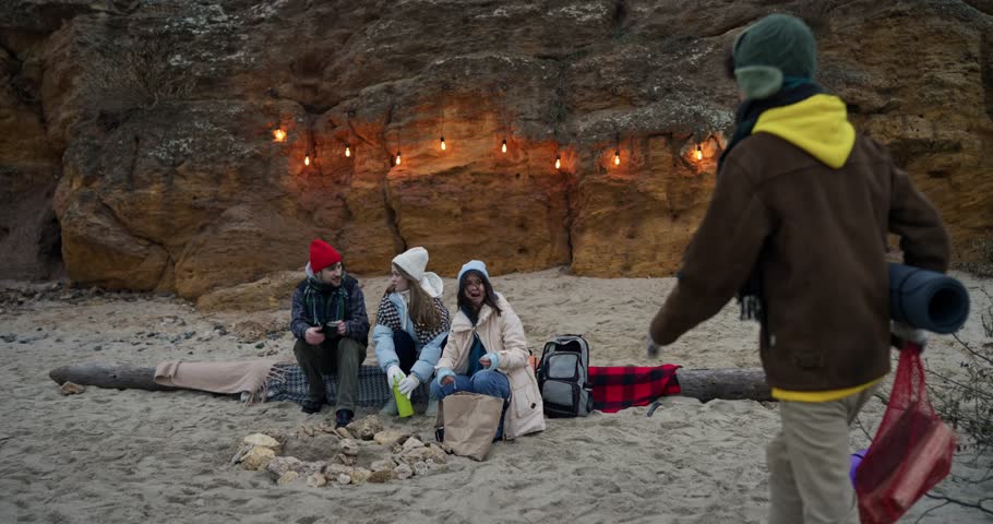 Happy guy meeting his friends while hiking on the sand at the beach