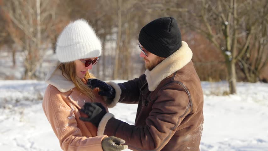 Couple enjoys playful moment in snowy landscape during winter outing