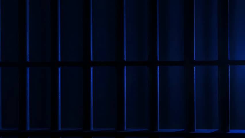 Prison Cell Bars Casting Shadows: Symbolizing Confinement and Loss of Freedom. metal prison cell bars casting shadows on the floor, representing themes of incarceration, confinement