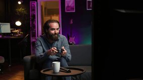 Focused man playing videogame in neon illuminated home, holding controller. Gamer hooked on enthralling game, excited to participate in online tournament, battling other players, camera B - Powered by Shutterstock - Get 15% off with code: PIKWIZARD15