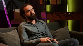 Bored gamer gaming on TV console using gamepad, eating popcorn, living sedentary lifestyle. Lazy man in home theatre playing videogames and consuming snacks, sitting on couch, camera A - Powered by Shutterstock - Get 15% off with code: PIKWIZARD15