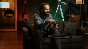 Cheerful gamer rushing home to play newly released game. Happy man jumping on couch, eager to play videogame on console, relaxing after hard day at work, camera A slow motion shot - Powered by Shutterstock - Get 15% off with code: PIKWIZARD15