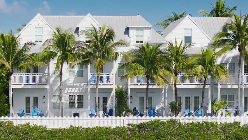 Enjoy a breathtaking aerial view of Sunset Key in Key West, Florida, featuring turquoise waters, swaying palm trees, and charming beachside properties along the scenic shoreline