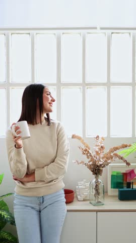 Woman drinking coffee at home by window