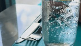 Macro view of club soda bubbles rising in a glass, set against a dining table with cutlery, in natural light - Powered by Shutterstock - Get 15% off with code: PIKWIZARD15